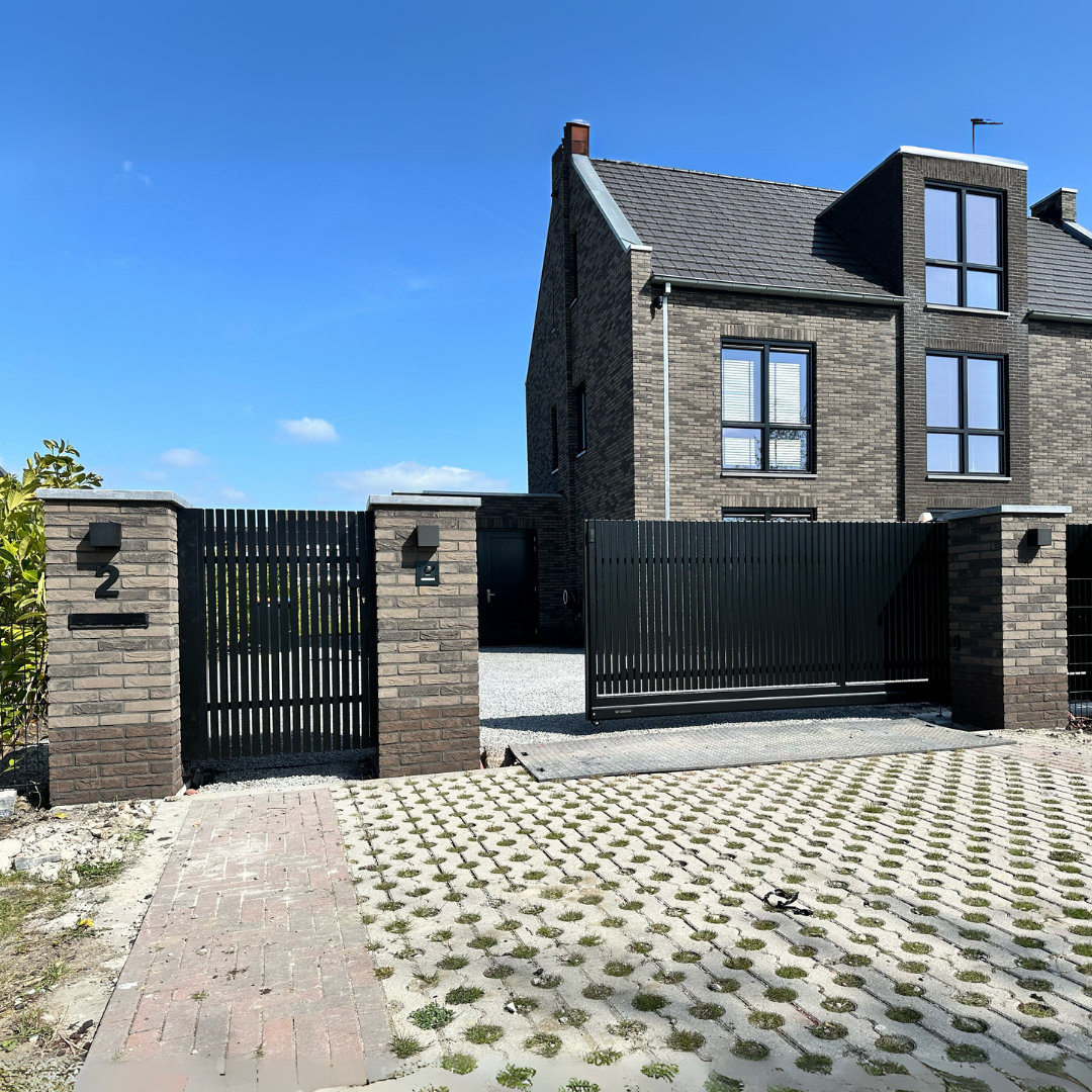 Zwarte stalen poort met gemetselde pilaren